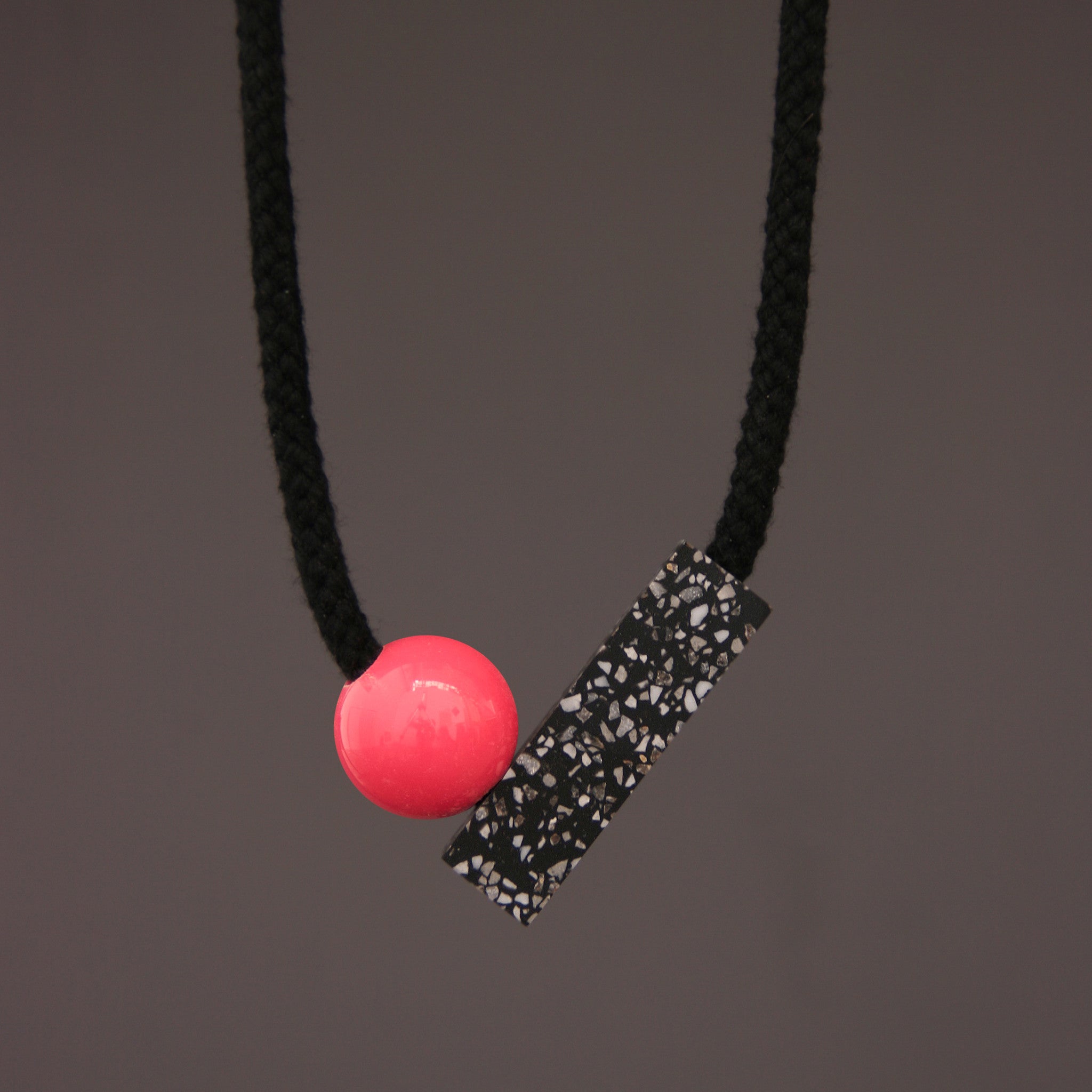 The Ad necklace is a minimalist and stylish design. It is composed of 2 main parts - A section of black corian with fine speckles of grey and white (60mm x 18mm) and a coloured ball (25mm).