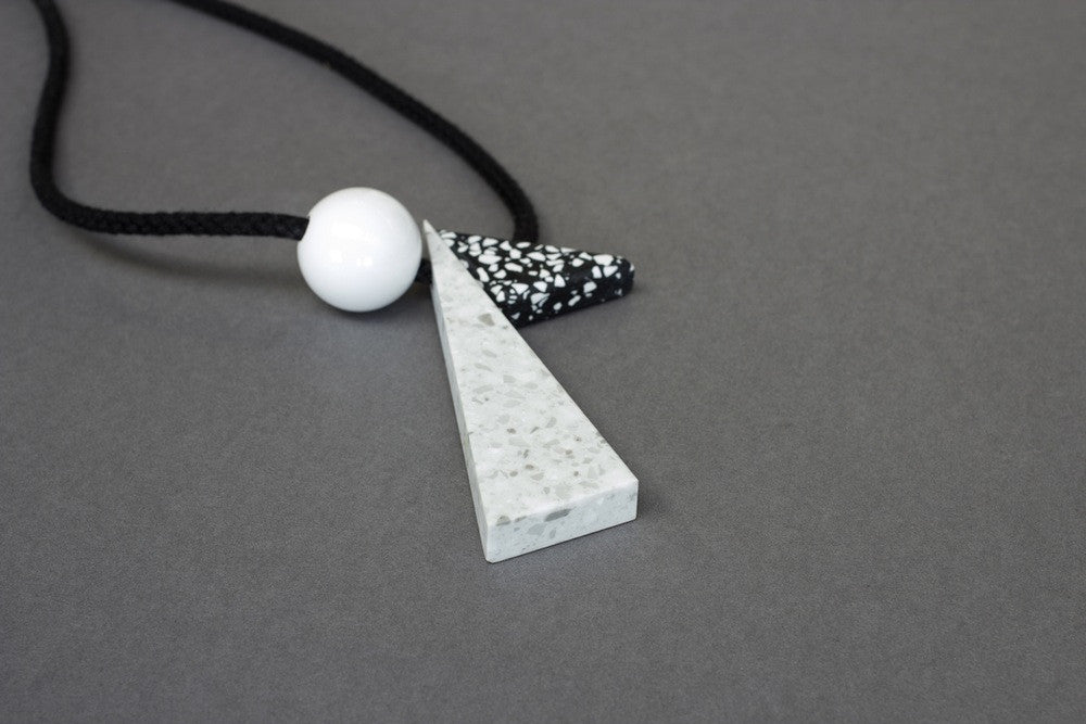 Bold and very striking statement necklace composed of 3 resin parts. Oskar is one of our classic geometric styles and is a bold statement worn on a plain top. Black and white speckled triangle, long silvery grey triangle (10cm) and a white ball (3cm)