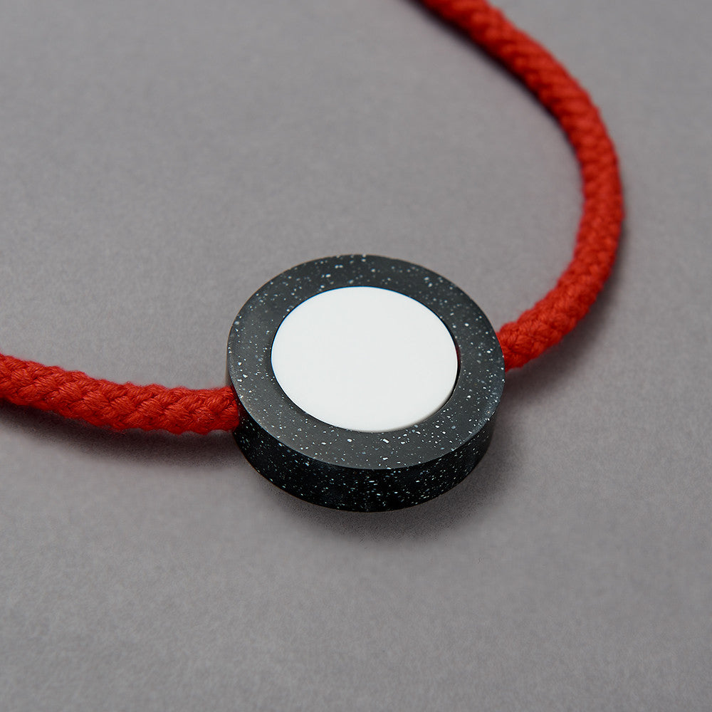 The Ed necklace is part of the collection we launched with Transport For London at Clerkenwell Design Week 2017.Bright and striking necklace. Bright red rope. Small yellow balls on the end of each rope. (15mm)Black speckled resin circle 40mm diameter x 10mm White resin circle which sits inside, 30mm x 10mm