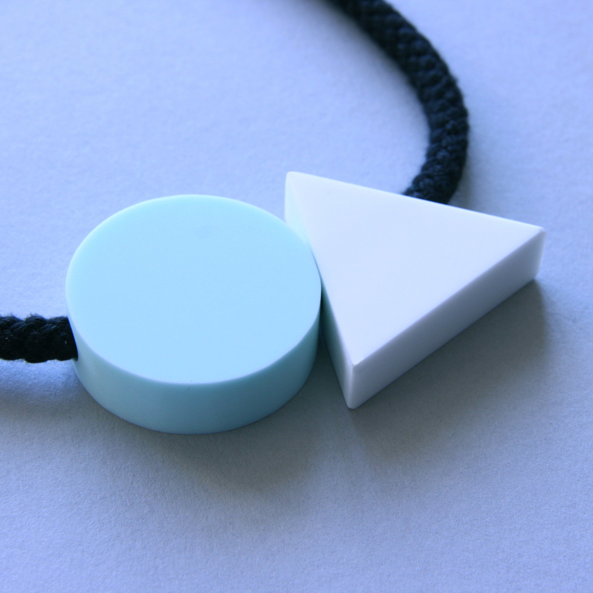 The Ellsworth necklace is a pleasing balance of 2 geometric shapes. A mint circle sits neatly beside a white triangle offering a striking and minimal addition to any outfit. A geometric statement necklace.