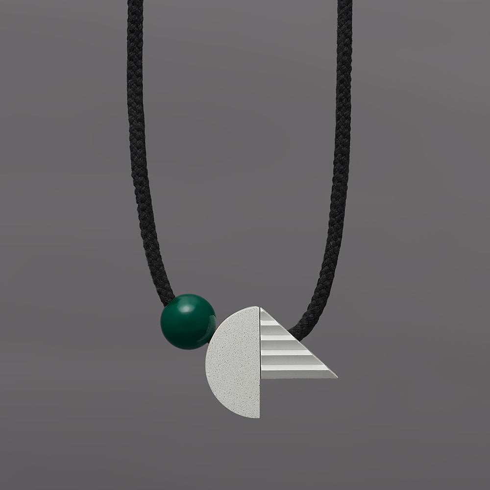 The pop necklace is composed of 2 handcast shapes. A lovely concrete-effect curve measuring 50mm x 25mm which sits beside a cast ridged triangle which measures 30mm x 45mm. The bright green ball (25mm) offers a pop of colour beside the understated concrete resin shapes.