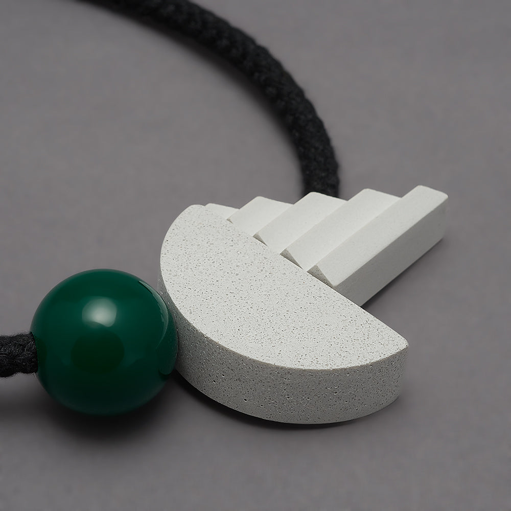 The pop necklace is composed of 2 handcast shapes. A lovely concrete-effect curve measuring 50mm x 25mm which sits beside a cast ridged triangle which measures 30mm x 45mm. The bright green ball (25mm) offers a pop of colour beside the understated concrete resin shapes.