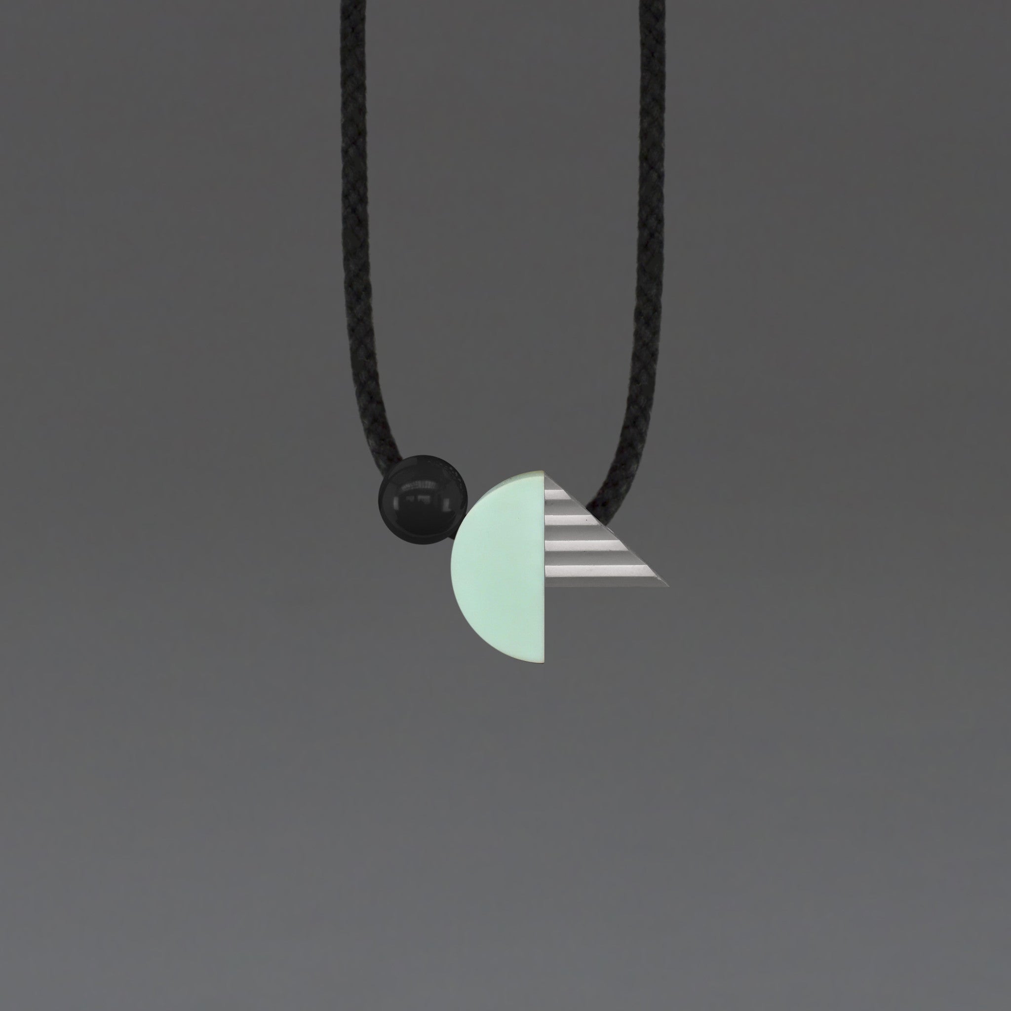 Striking geometric necklace composed of a mint resin curve and a hand cast ridged concrete-look resin triangle. The unusual mix of materials creates an intriguing necklace of varying textures and shapes.