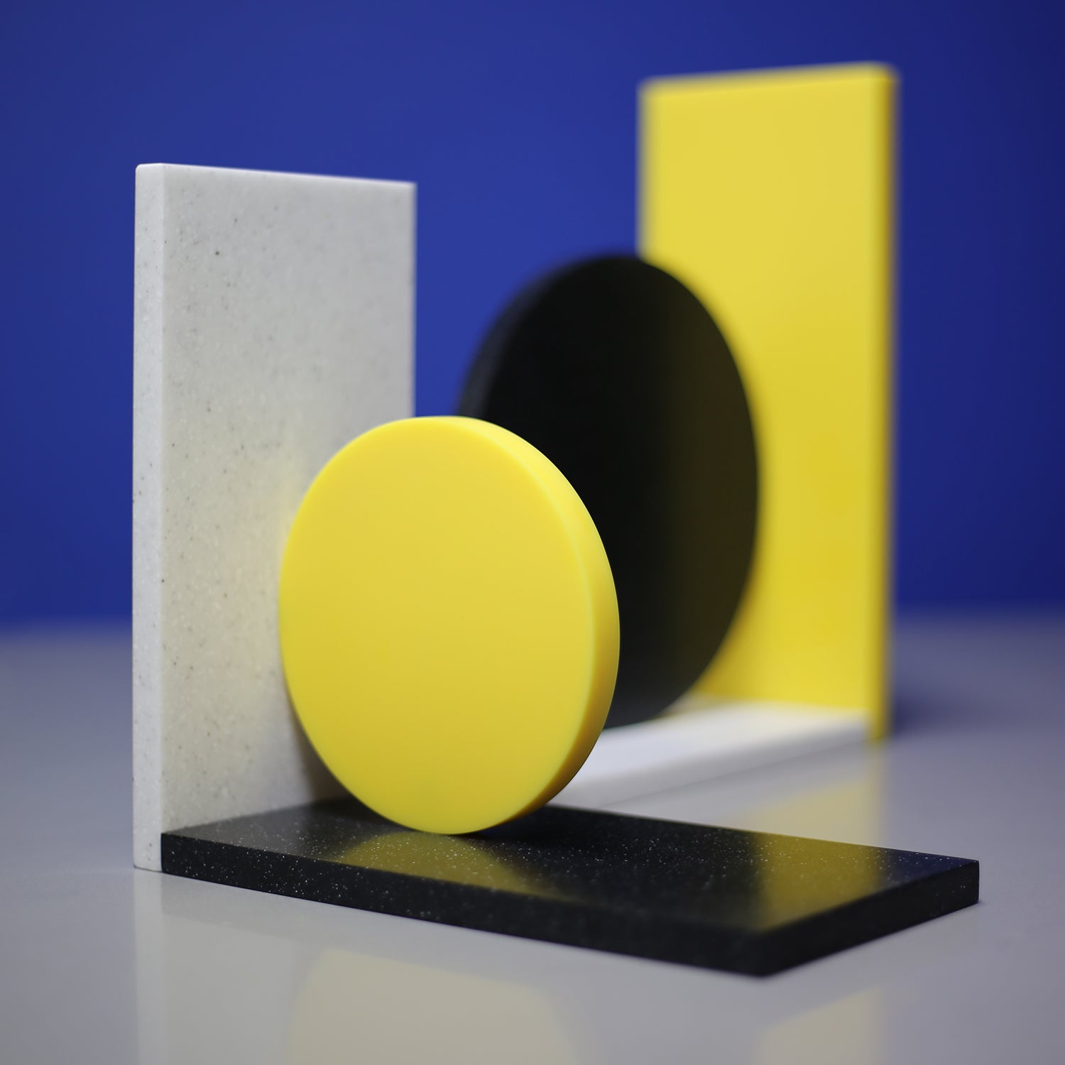 Corian Dot Bookends made to order. Asymmetrical design makes each end different. Yellow corian, black speckled corian, light grey speckled corian.  A colourful addition to any shelf!