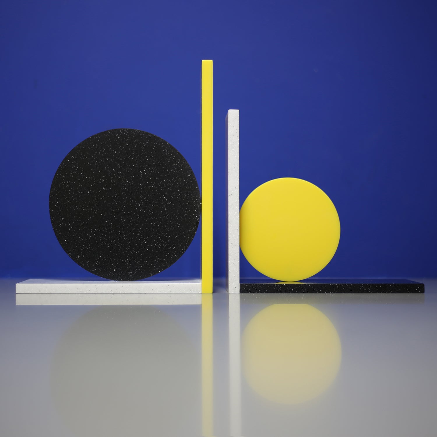 Corian Dot Bookends made to order. Asymmetrical design makes each end different. Yellow corian, black speckled corian, light grey speckled corian.  A colourful addition to any shelf!