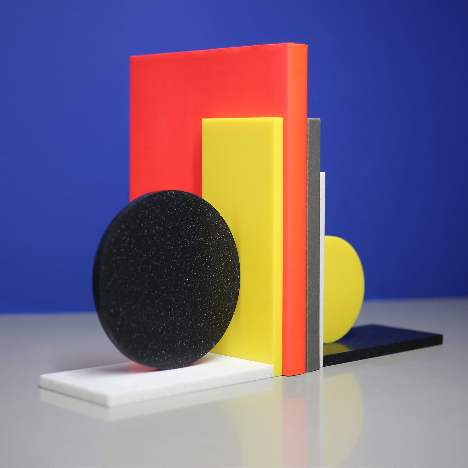 Corian Dot Bookends made to order. Asymmetrical design makes each end different. Yellow corian, black speckled corian, light grey speckled corian.  A colourful addition to any shelf!