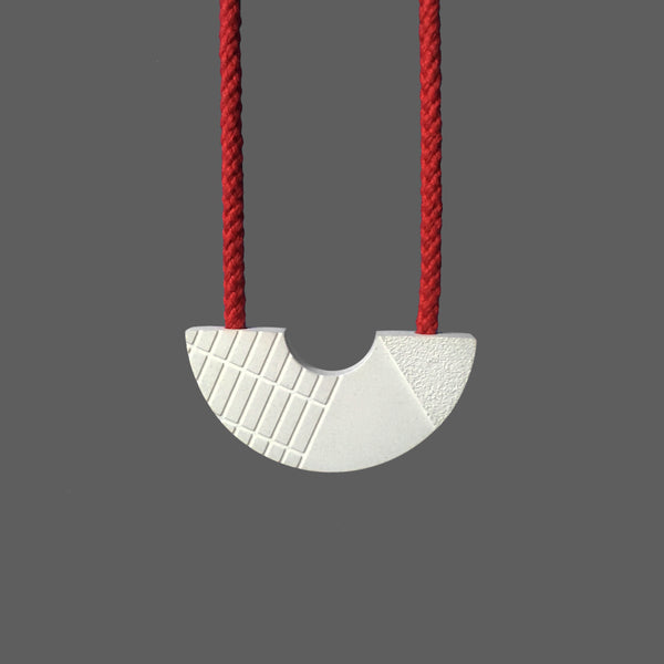 The Emile necklace was inspired by the architecture of the Barbican centre in London. It is a striking necklace made of jesmonite with an intricate relief pattern. The necklace hangs on red cord with a full drop of 45cm. Handmade in our London studio.
