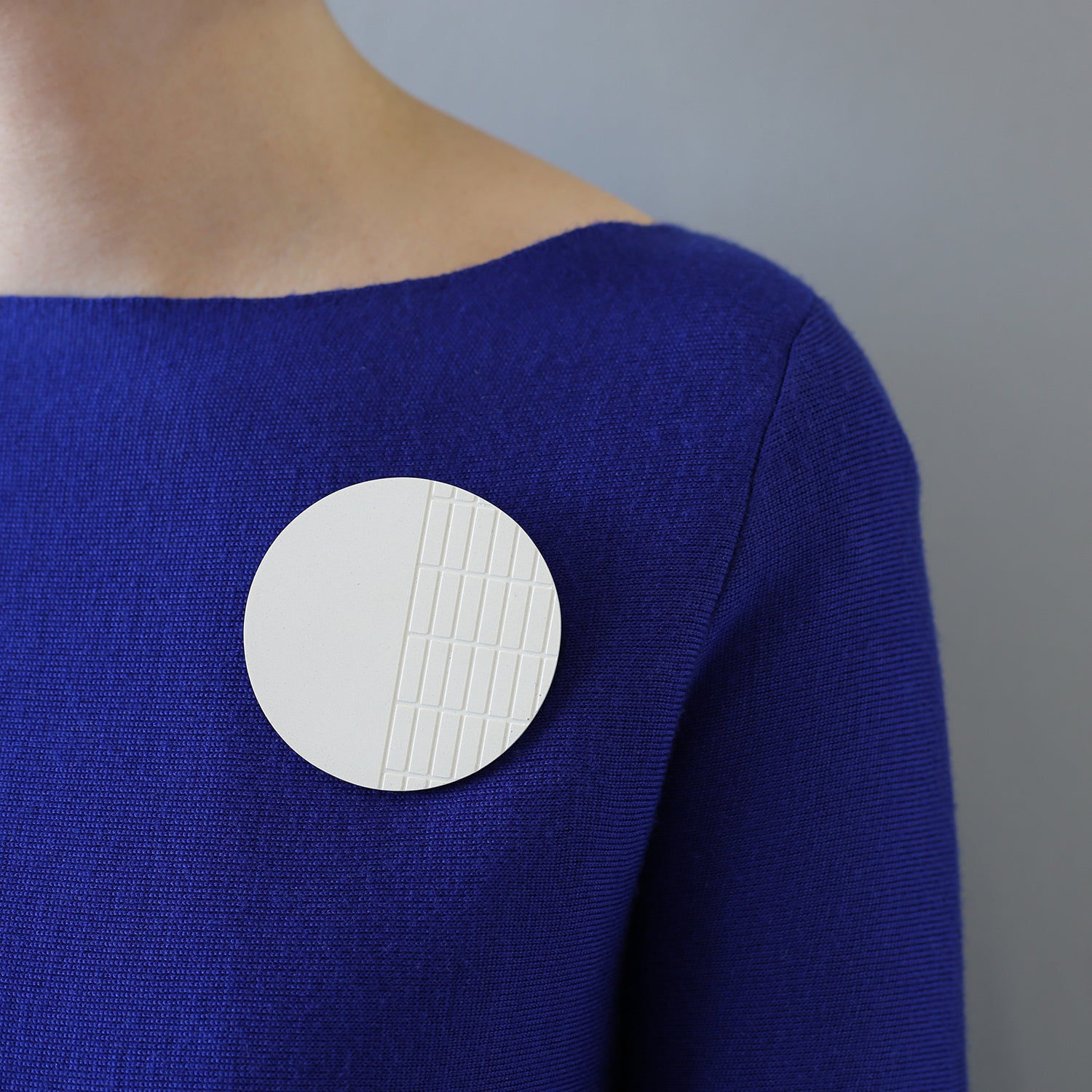 Handcast brooch inspired by the brutalist architecture of London's Barbican centre. This circular brooch has a fine grid recessed over half of the surface. Each brooch is cast by hand in our south London studio and comes in branded gift box. (7cm diameter) 
