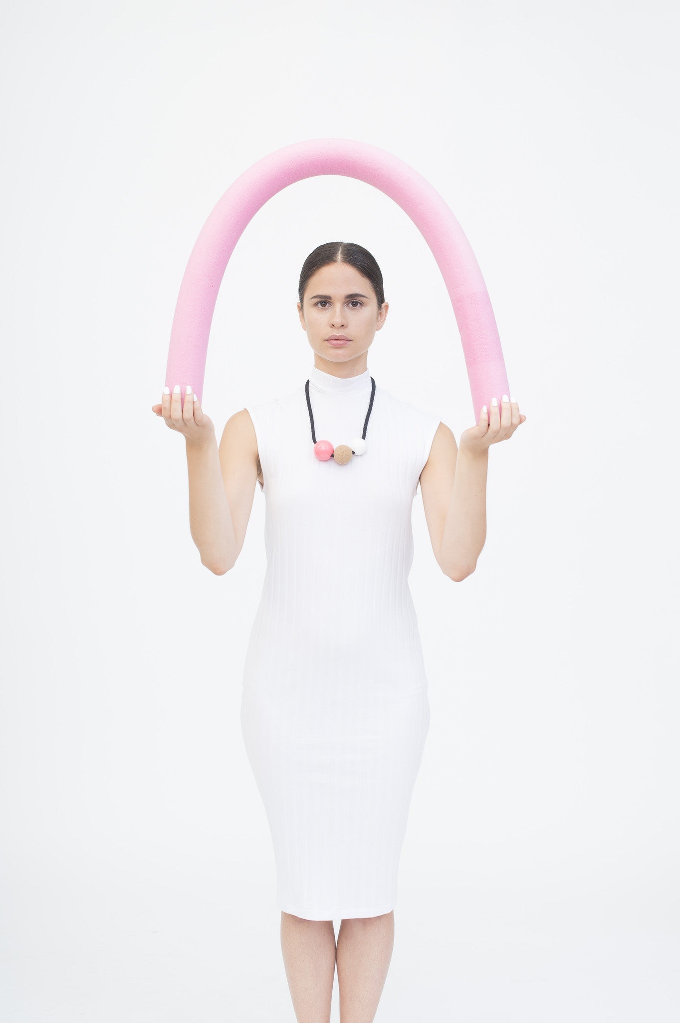 This is an image of a model wearing our Anni necklace. Bold, striking statement necklace composed of resin and cork balls on black cord. This design is a lovely mix of textures and materials and looks great on a simple top or dress.  Handmade in our London studio. Comes packaged in a branded kraft tube.