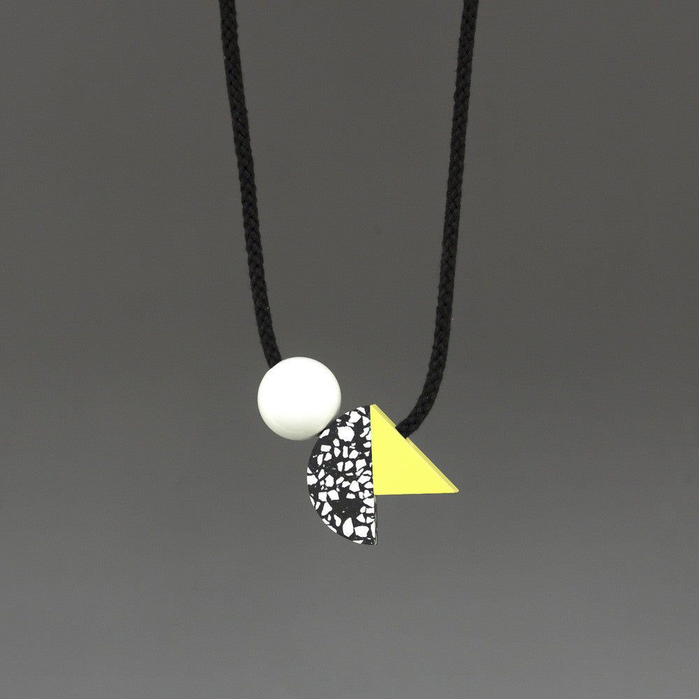 Ella is a bold necklace composed of 3 geometric shapes on black cord. Black and white speckled curve, yellow triangle and white ball. Handmade in our London studio. A contemporary statement necklace.