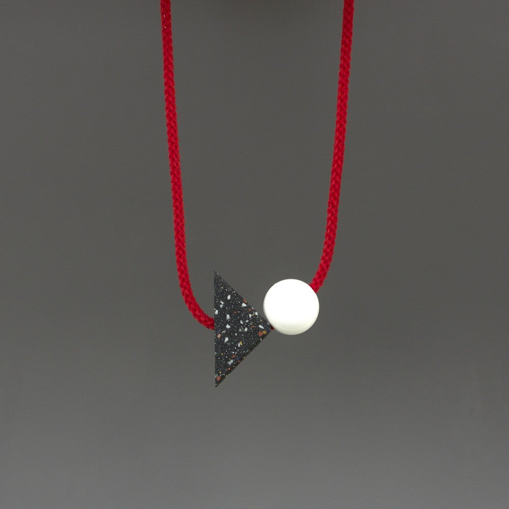 Konstantin is a bold and striking geometric necklace composed of resin parts on bright red cord. Resin triangle is black with little coloured speckles. Measures 70 x 50mm  Necklace can be worn high at neck length or as a longer pendant due to adjustable cord.Full drop is 45cm Handmade in our London studio.