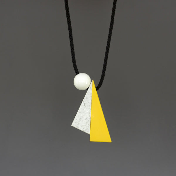 Hannes is a striking geometric necklace composed of 3 geometric shapes - 2 long triangles in yellow and marbled white and a resin ball. Necklace can be worn at varying lengths due to the wooden ball behind the neck which can be moved up & down to adapt necklace height. 