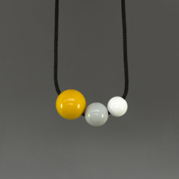Bold, striking and fun statement necklace composed of three bright resin balls. Yellow, grey and white shiny resin balls on black cord. 