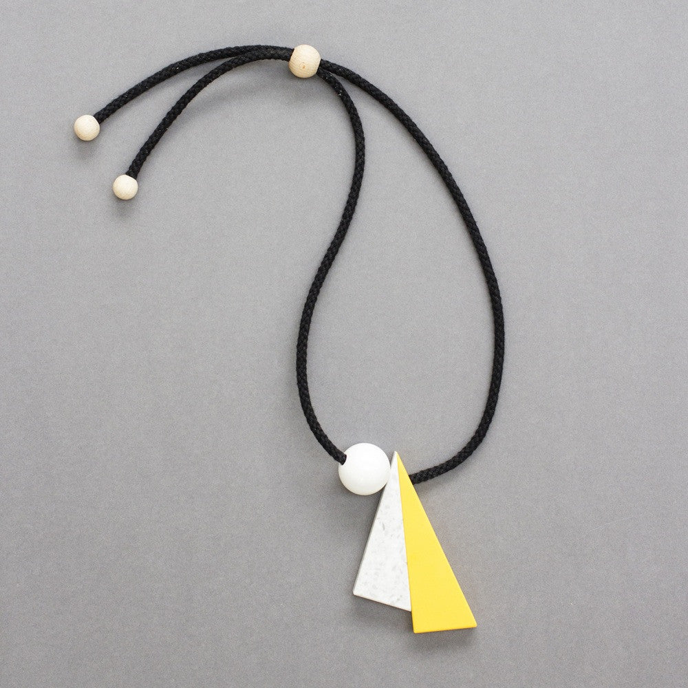 Hannes is a striking geometric necklace composed of 3 geometric shapes - 2 long triangles in yellow and marbled white and a resin ball. Necklace can be worn at varying lengths due to the wooden ball behind the neck which can be moved up & down to adapt necklace height. 