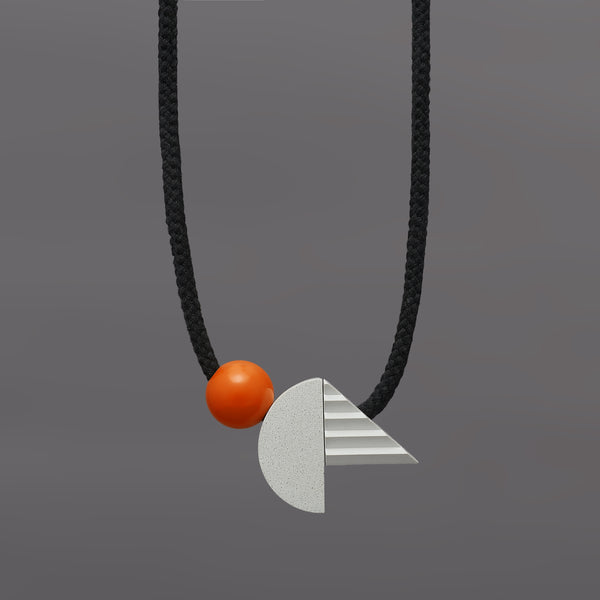 The pop necklace is composed of 2 handcast shapes. A lovely concrete-effect curve measuring 50mm x 25mm which sits beside a cast ridged triangle which measures 30mm x 45mm. The bright orange ball (25mm) offers a pop of colour beside the understated concrete resin shapes.